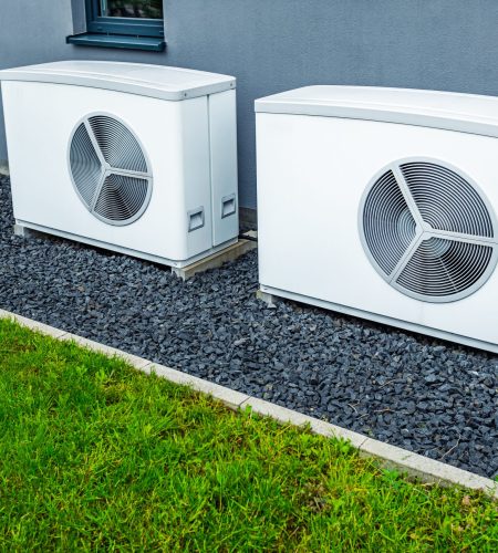 Two air source heat pumps installed outside of new and modern city house, green renewable energy concept of heat pump