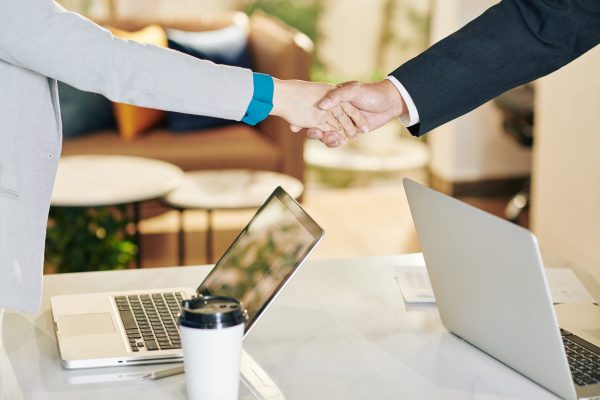 Close-up image of businessman and businesswoman shaking hands after discussing work at meeting